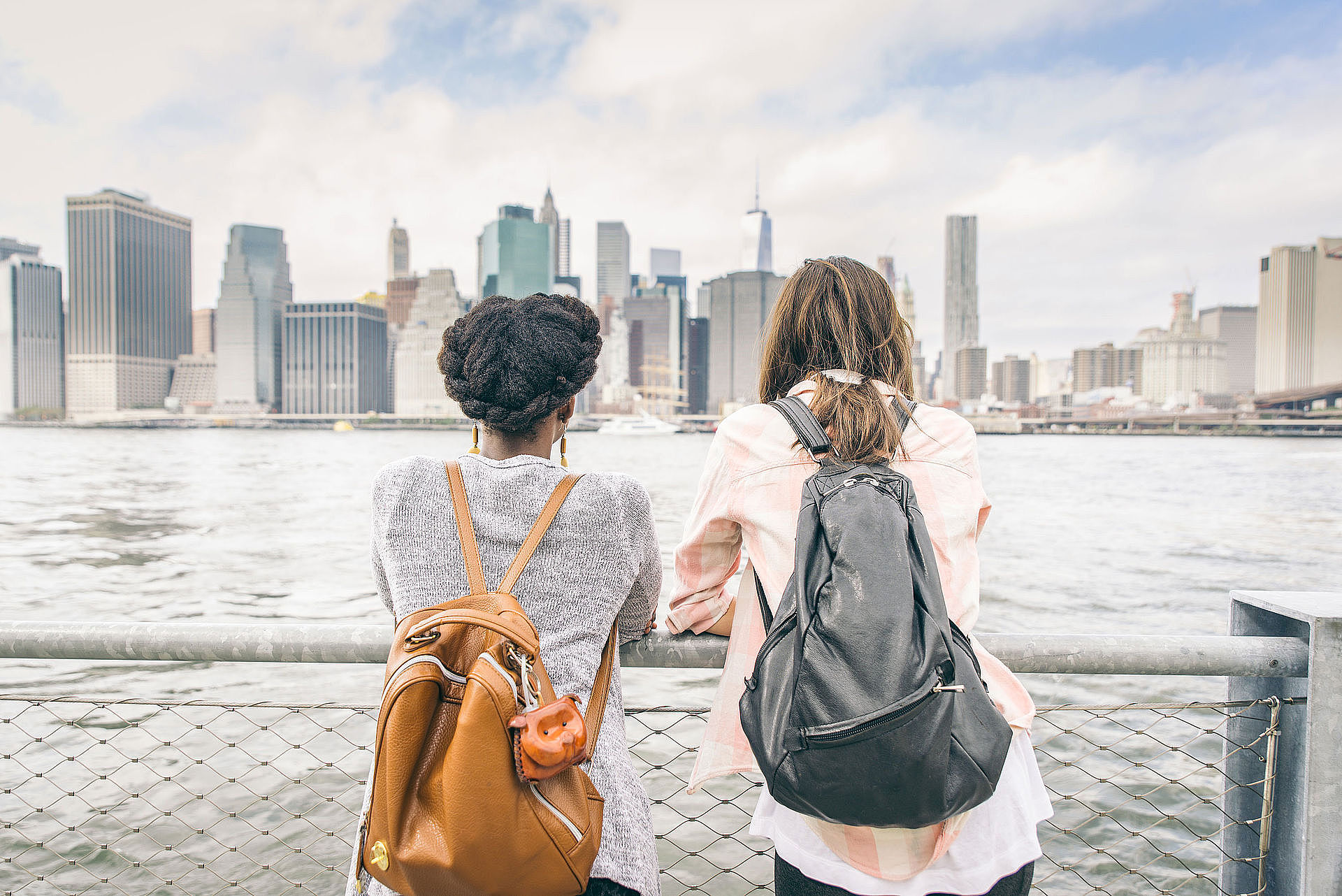 zwei junge Frauen von hinten, blickend auf die Skyline einer Stadt