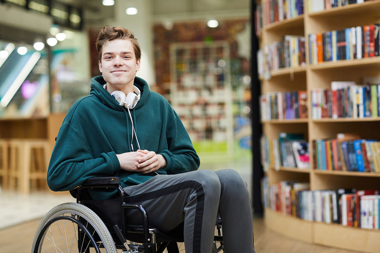 Student im Rollstuhl vor Bücherregal