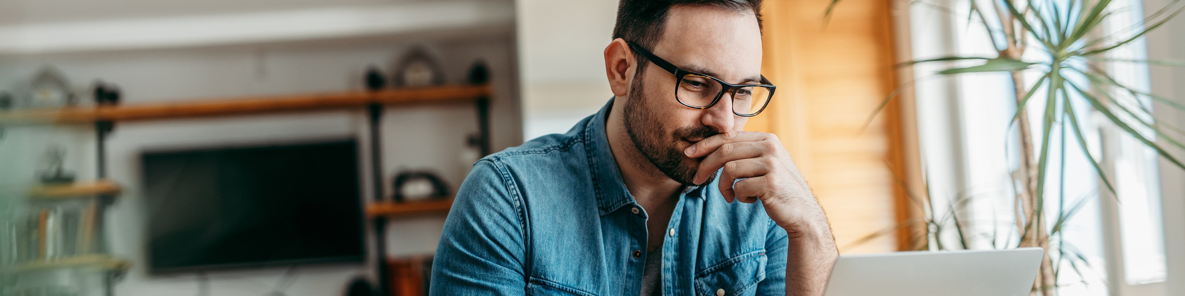 Ein Mann sitzt mit seinem Laptop an einem Tisch