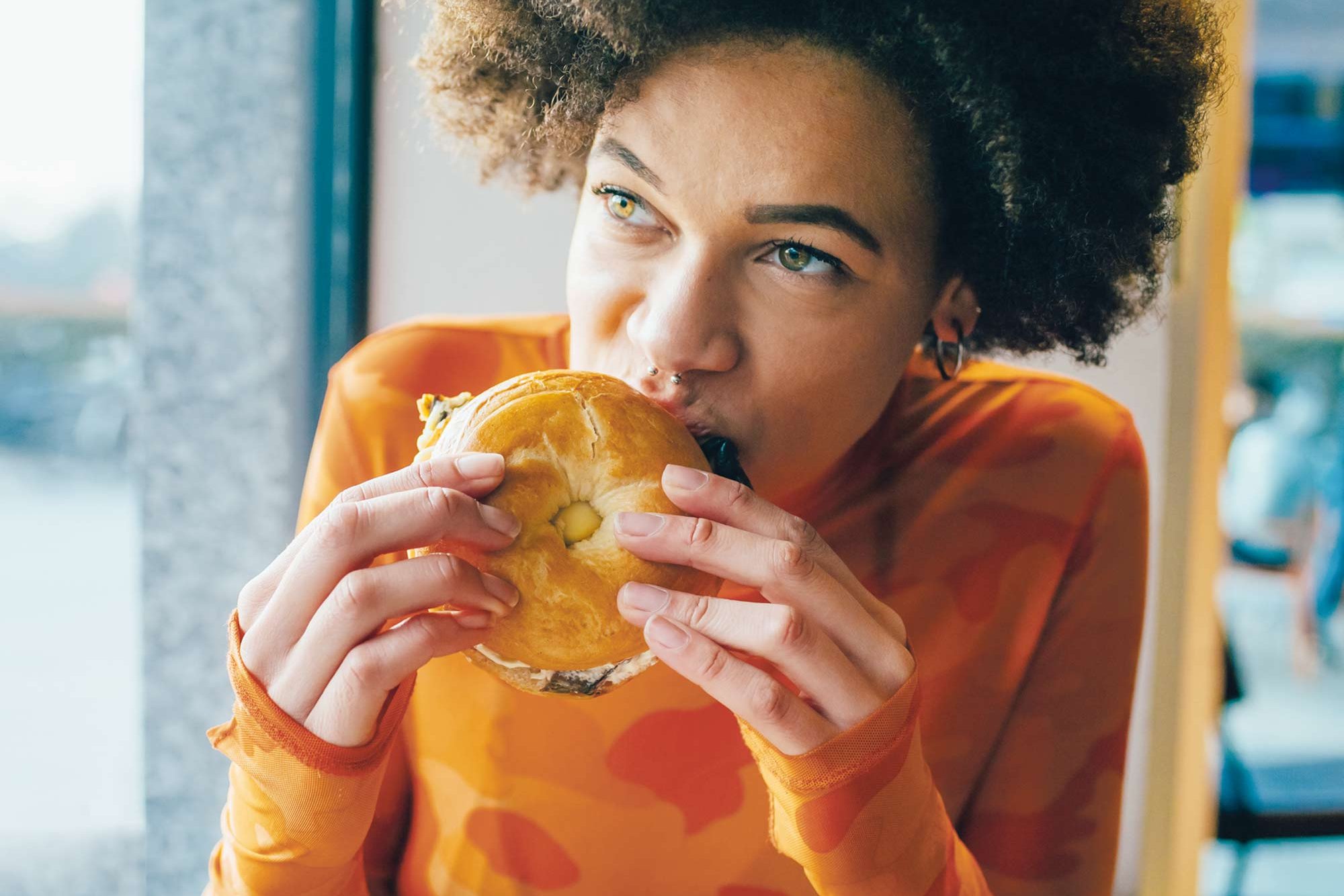Junge Frau, die einen Bagel isst