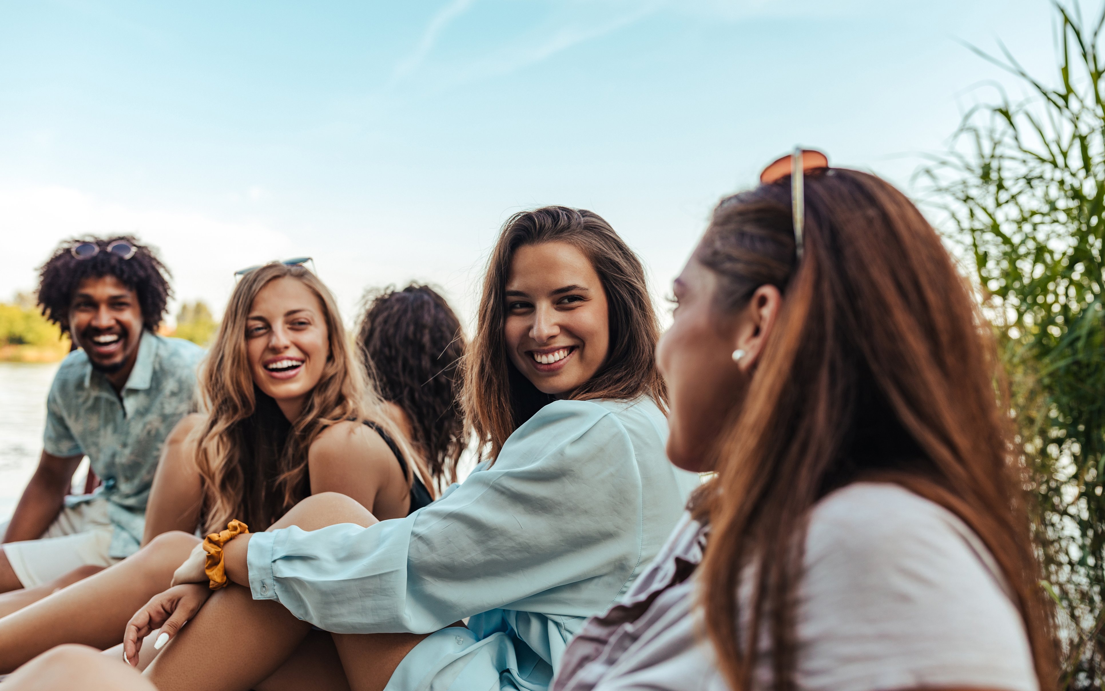 Gruppe junger Leute sitzt am Wasser