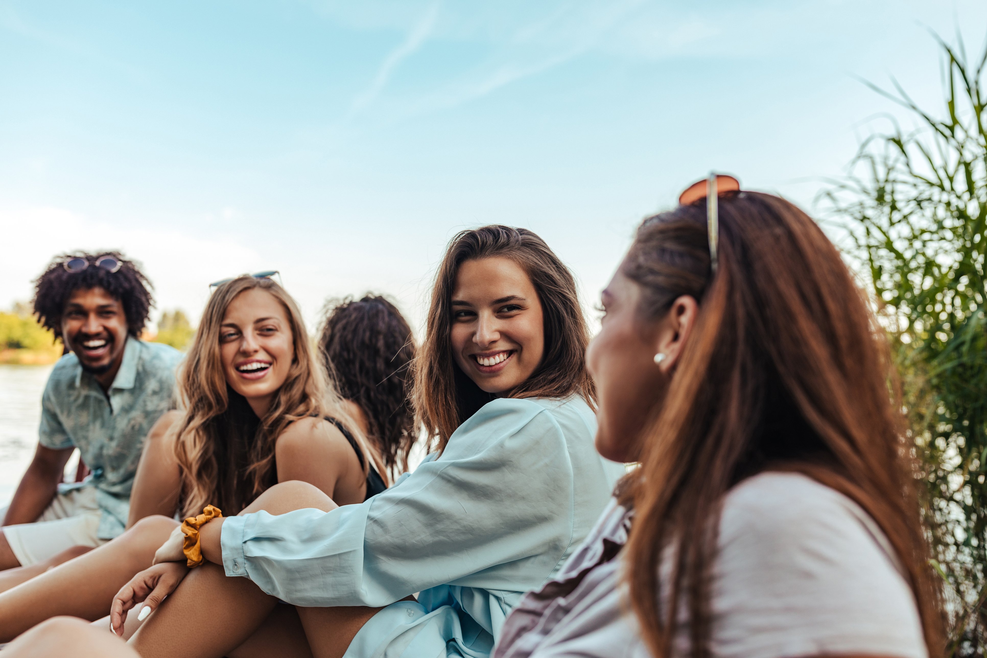 Group of young people sitting by the water