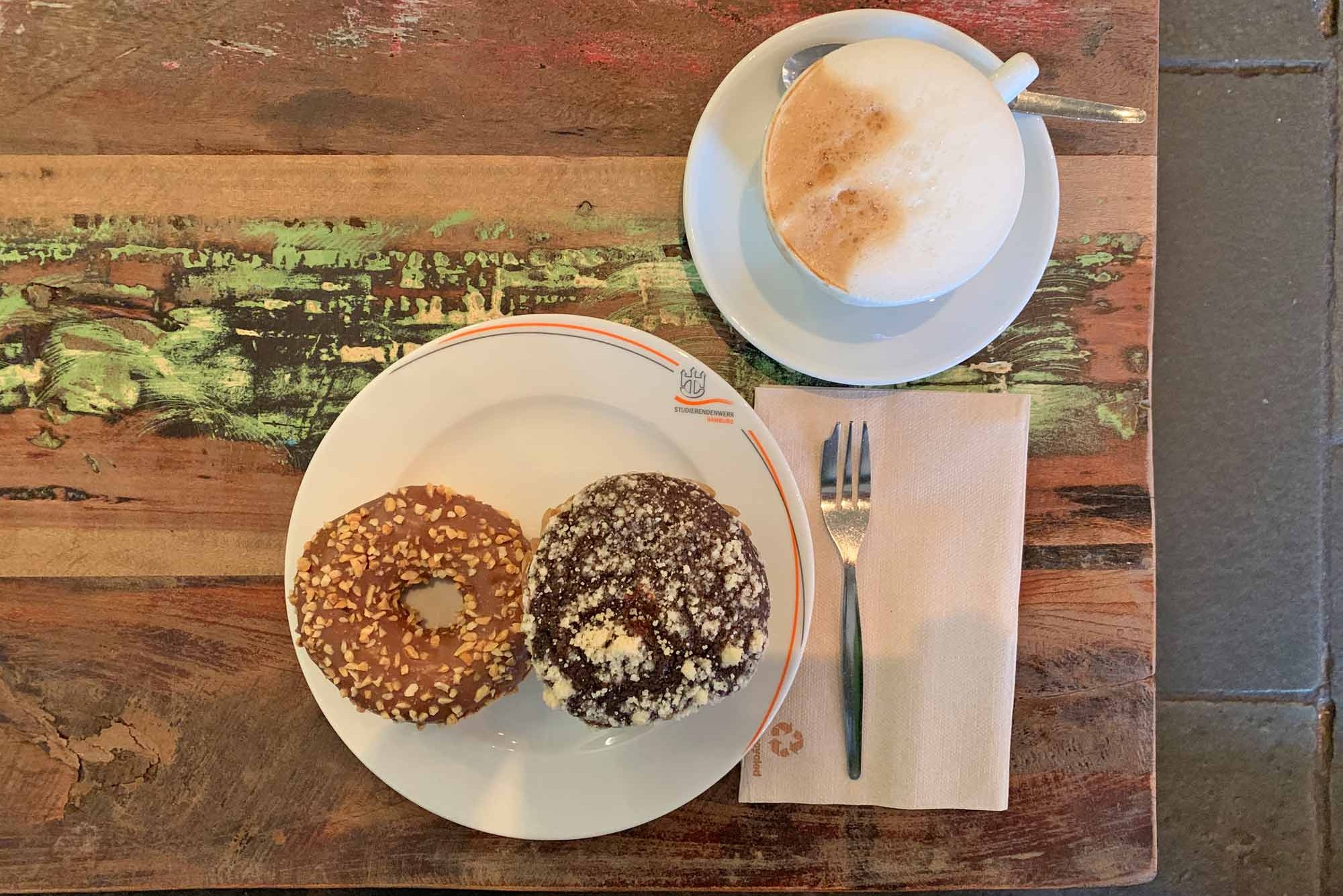 Cappuccino and a plate with a bagel and chocolate muffin at Café CampusBlick