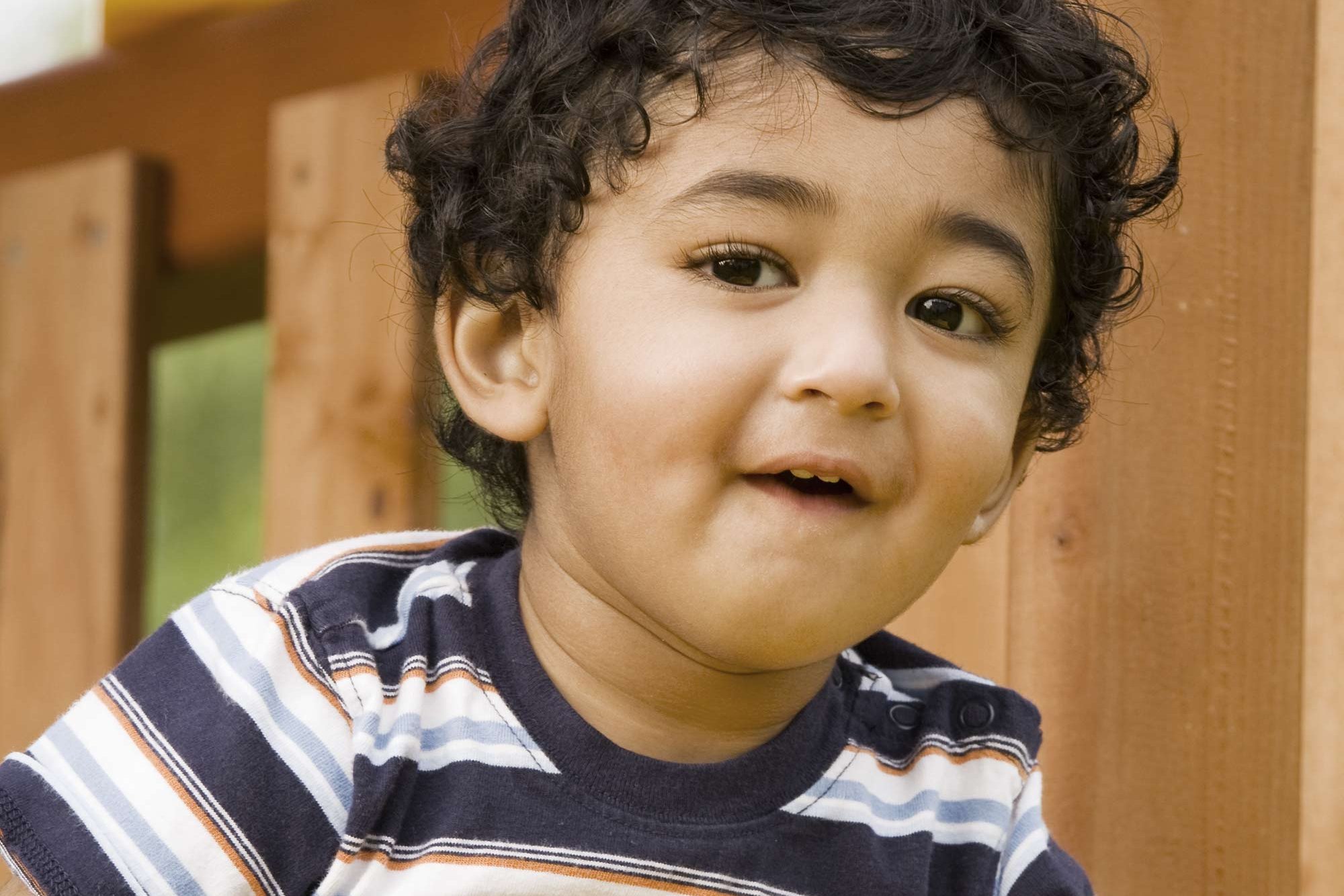 Kindergarten child in front of a fence.