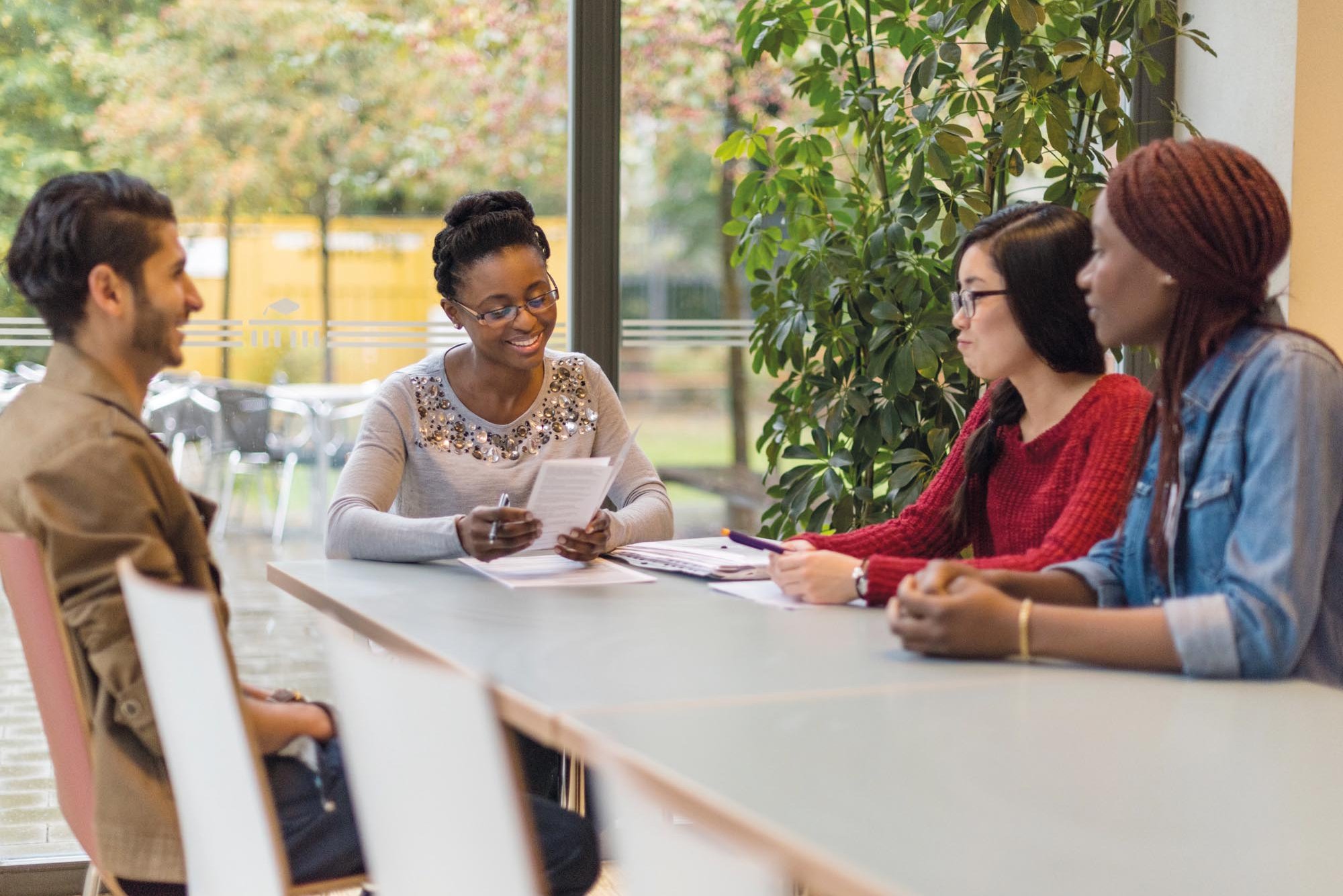 Four people are sitting at a table in a consultation situation.