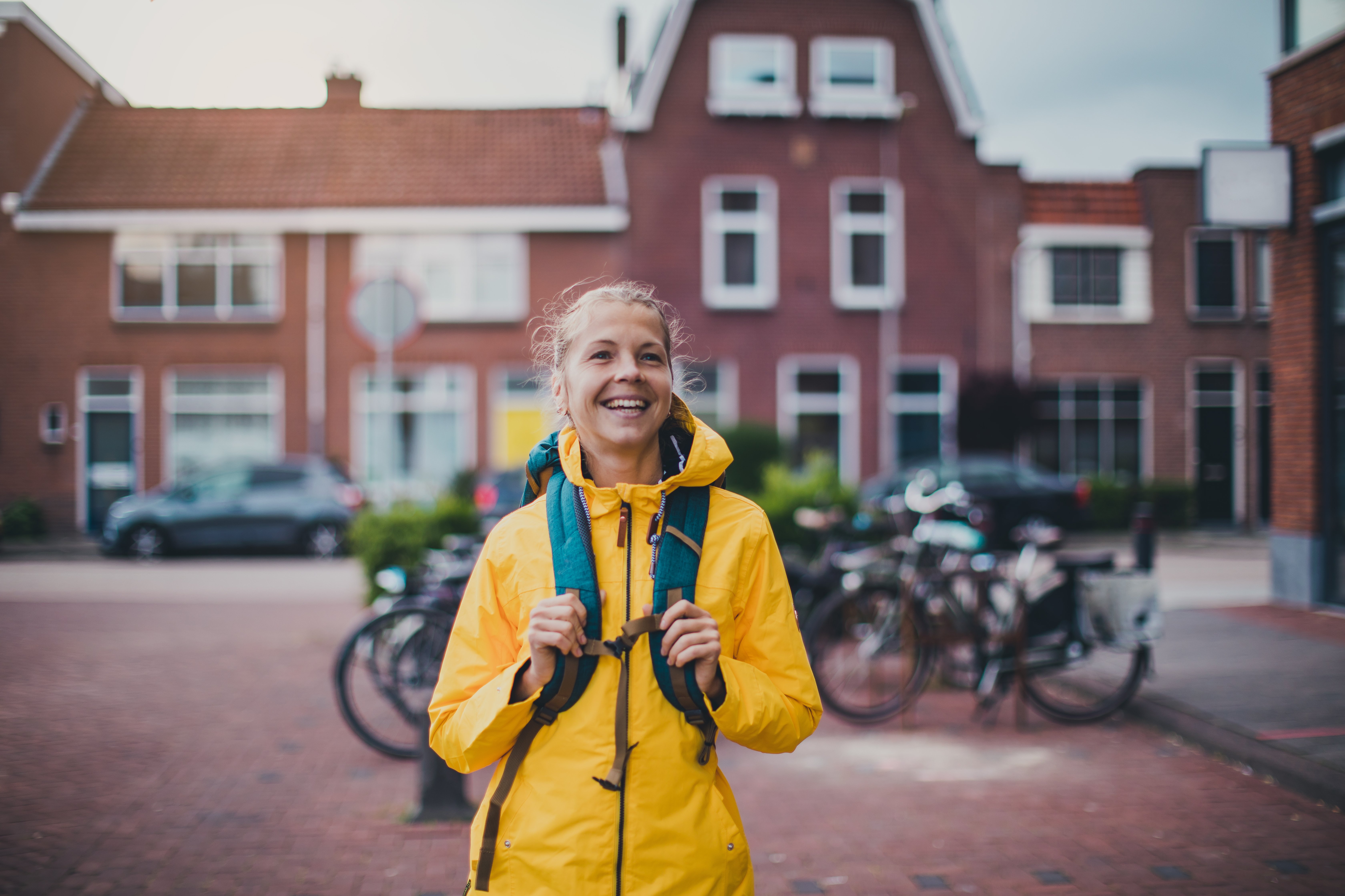 Studentin mit gelber Regenjacke und Rucksack