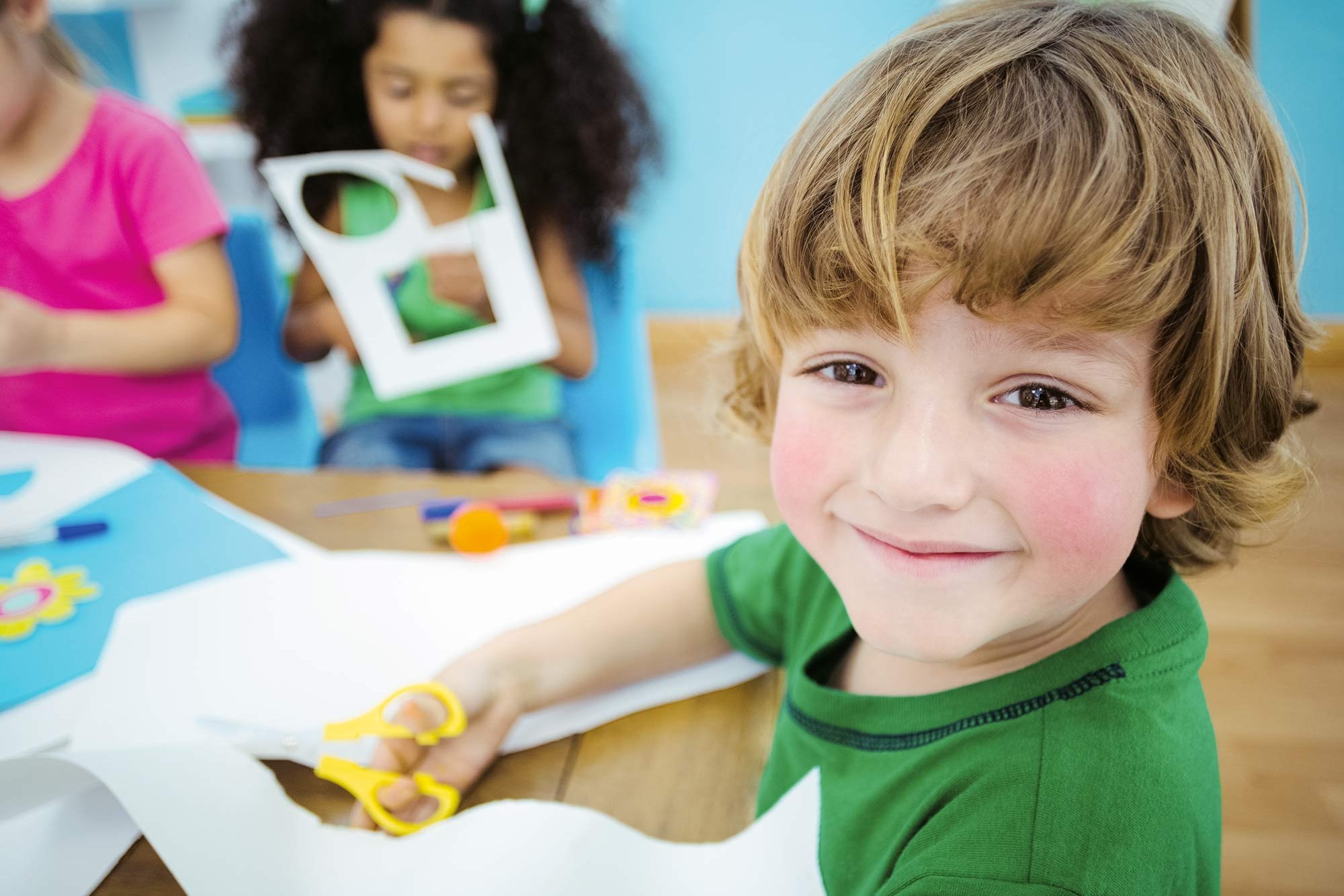 Three toddlers cutting paper with scissors