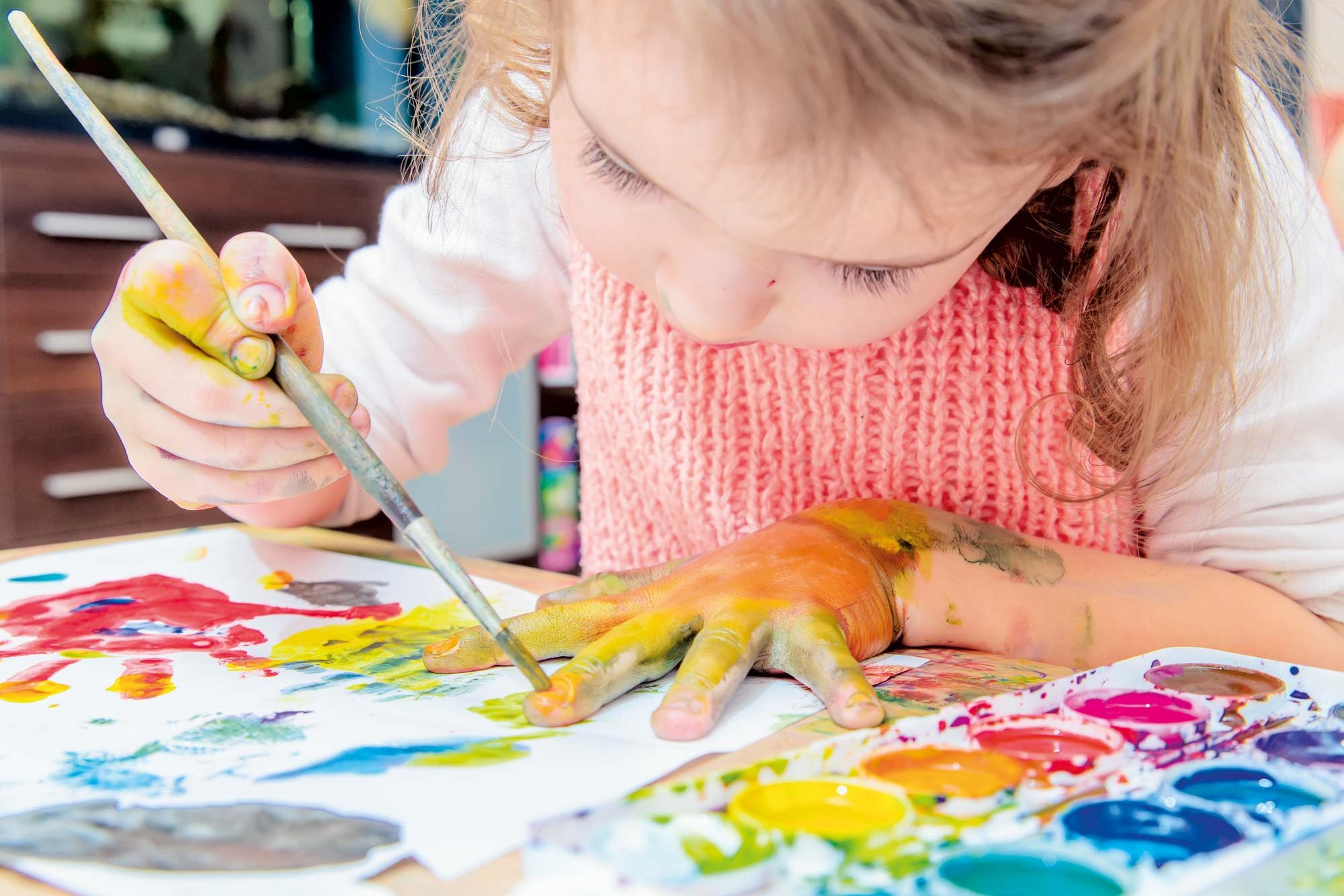 A little girl paints her hands