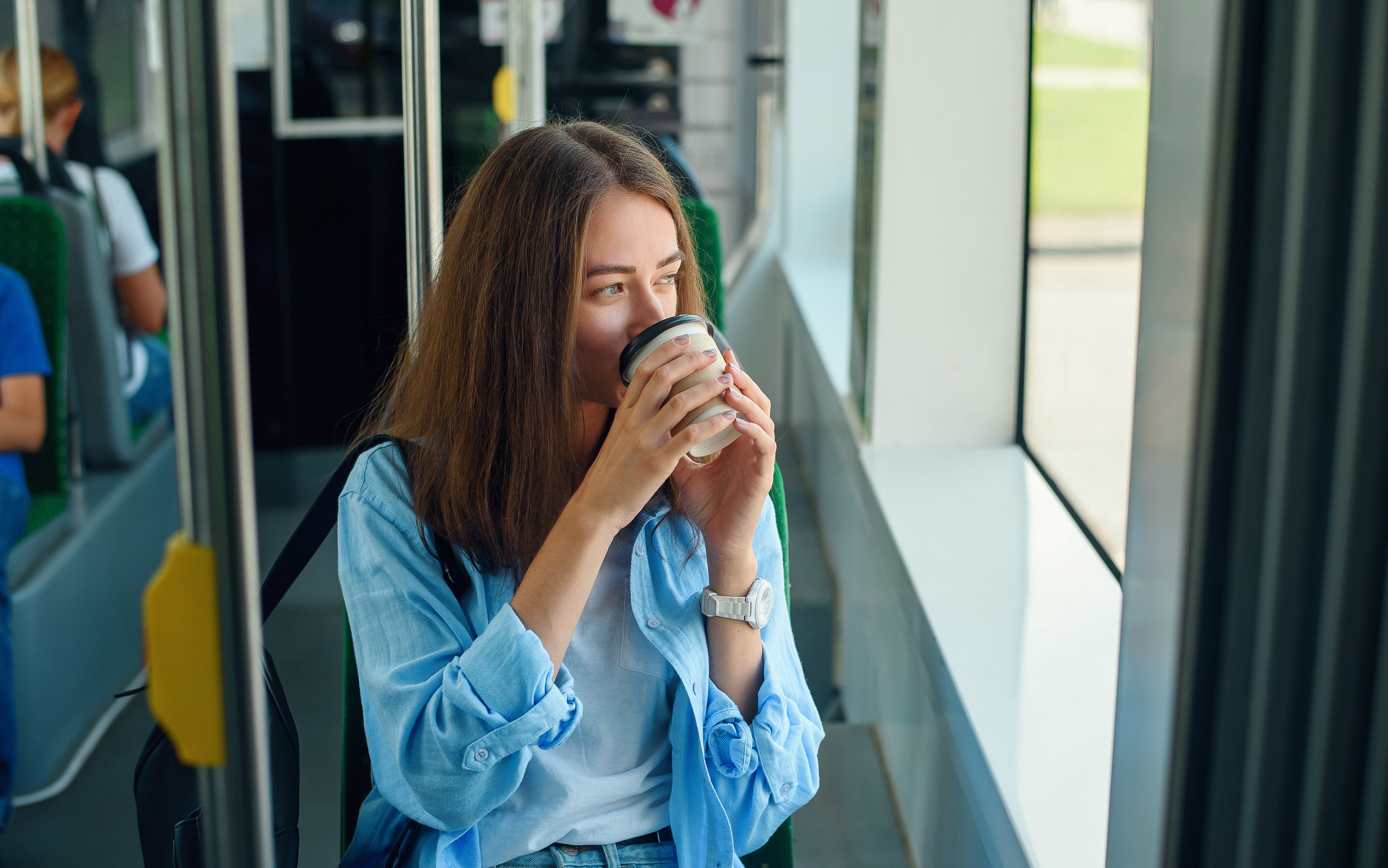 Studentin im Bus, einen Coffee to go trinkend