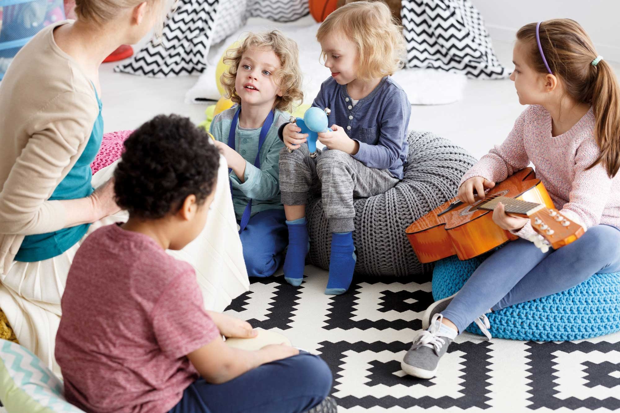 Erzieherin musiziert mit vier Kindern