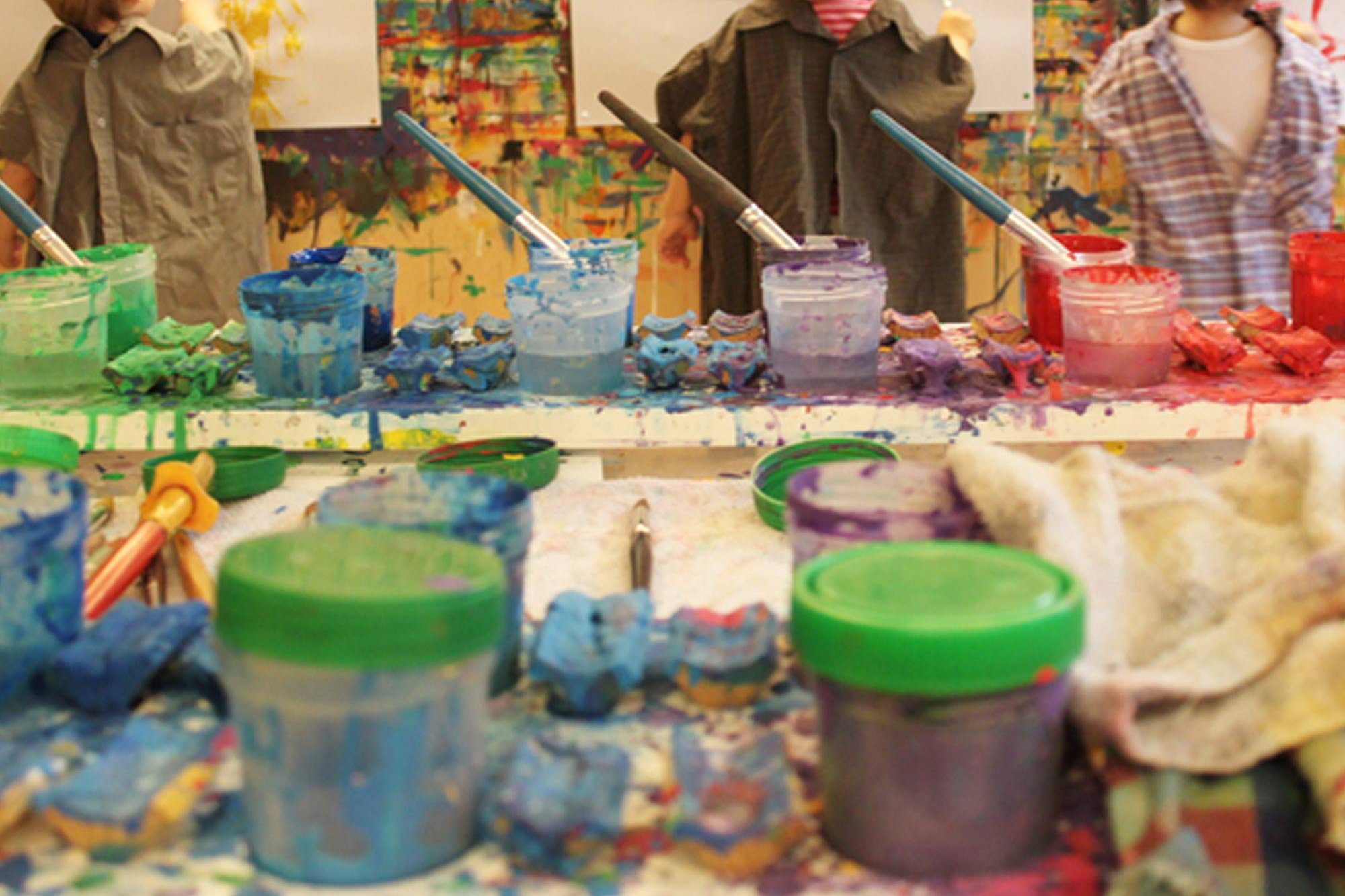 Children paint with different colors and brushes.