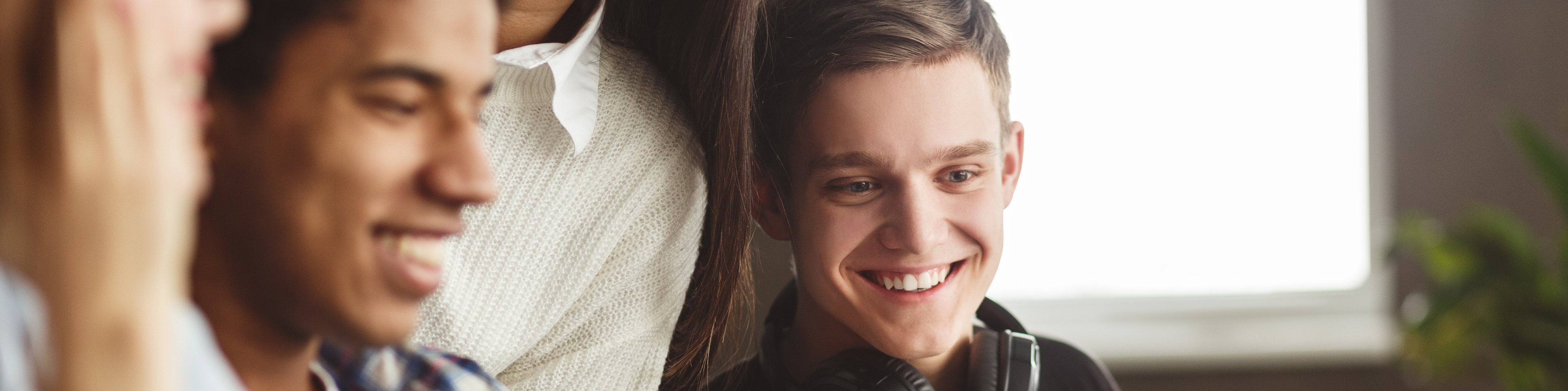 Vier Studierenden sitzen an einem Tisch und schauen auf einen Laptop
