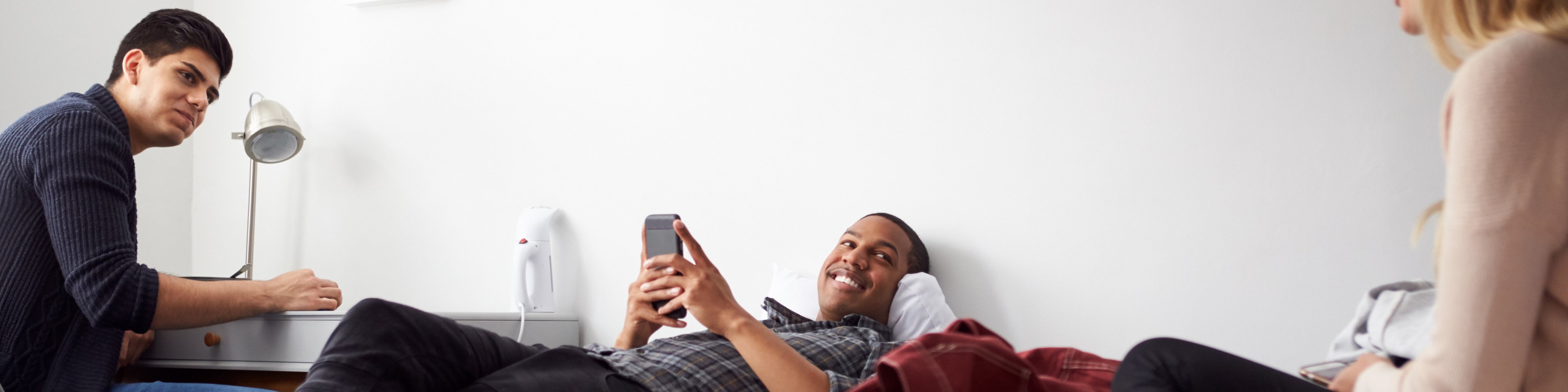 Three students are chatting in a student room.