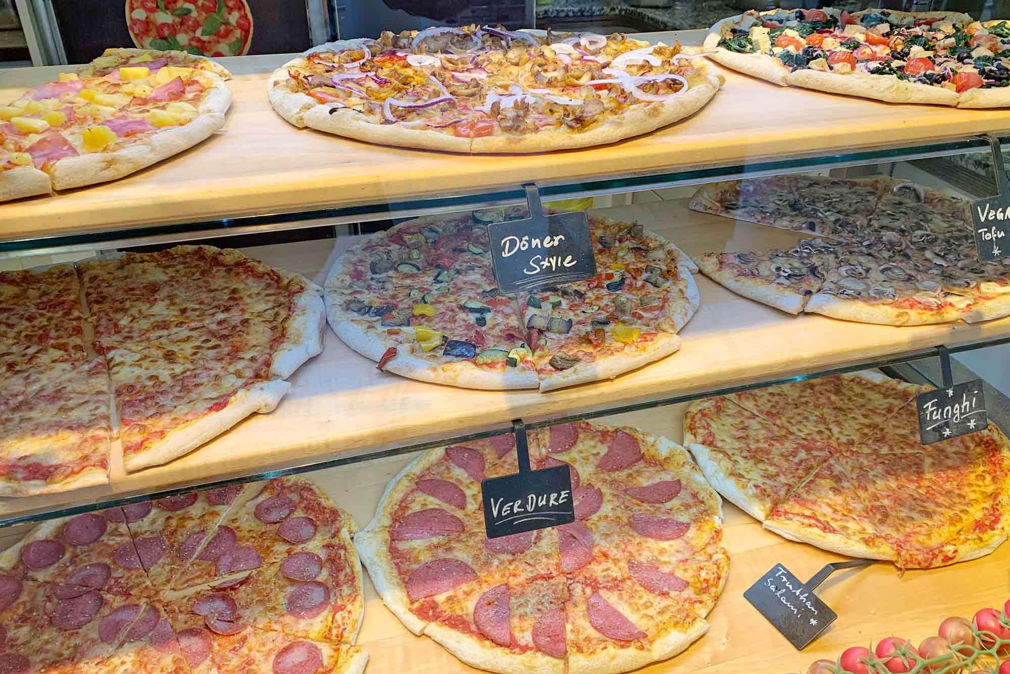 Pizza display case with a selection of pizzas at PizzaBar Harburg