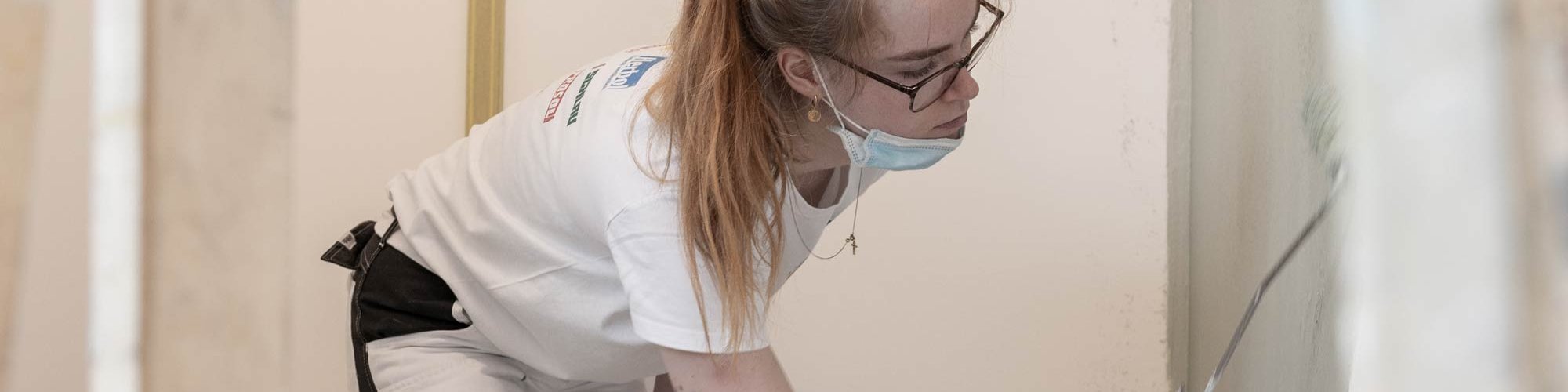 Auszubildende streicht eine Wand