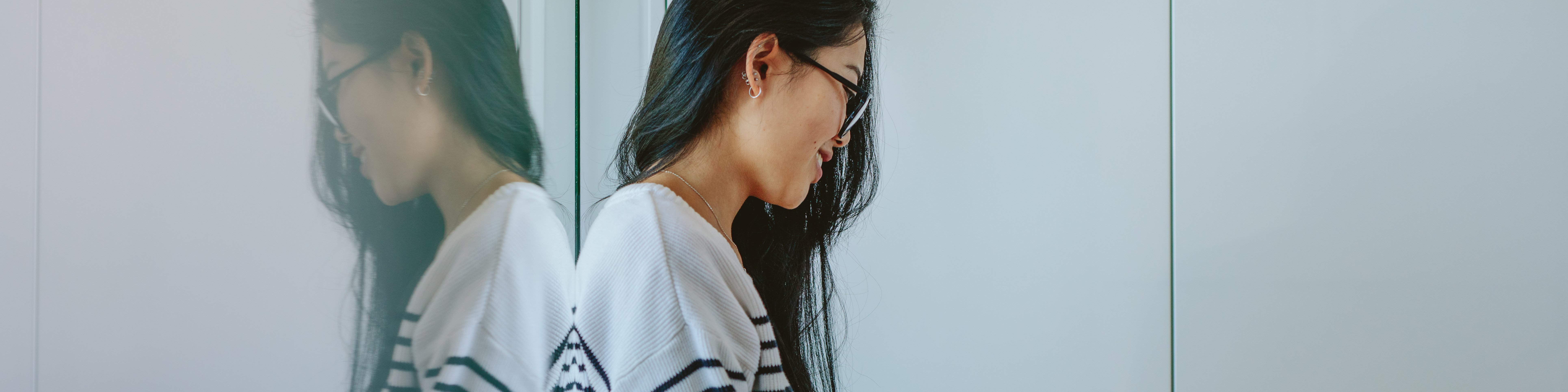 Frau mit Laptop sitzt auf dem Boden gegen eine Scheibe gelehnt 