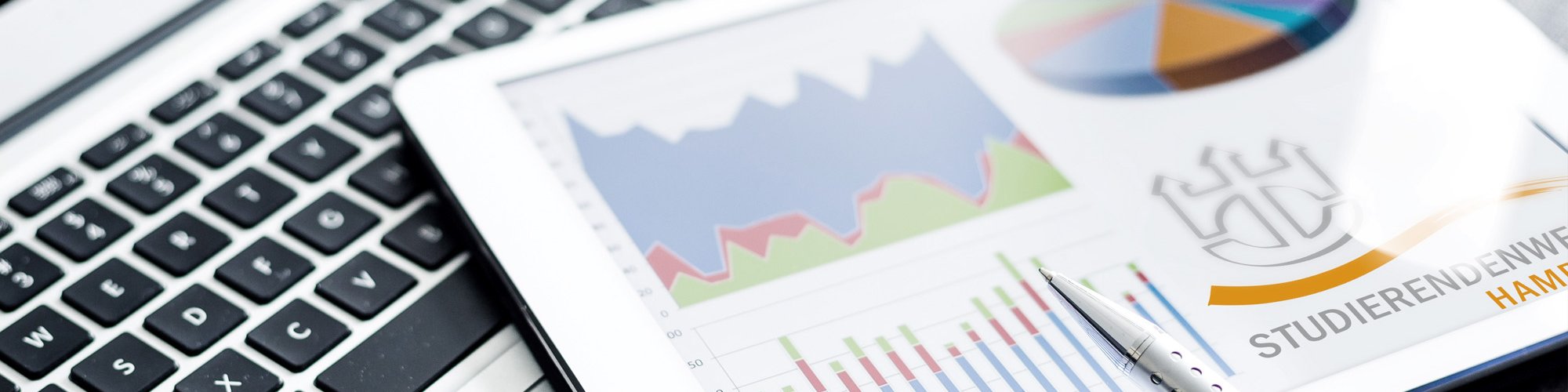 Aufgeklappter Laptop mit Zeitung und Stift 