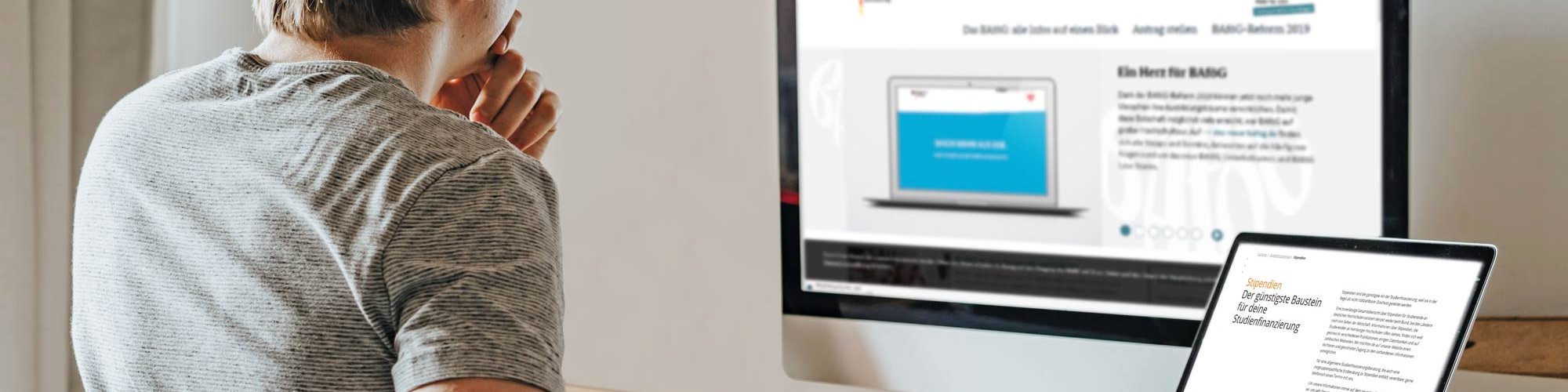 Young man sitting at his desk in front of his PC and laptop