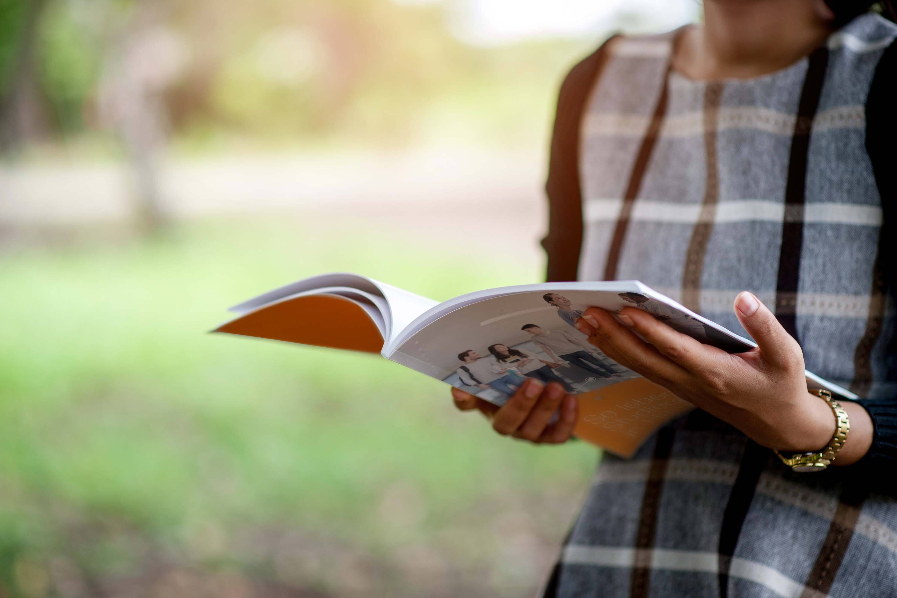 Frau im Park mit einem Magazin in den Händen