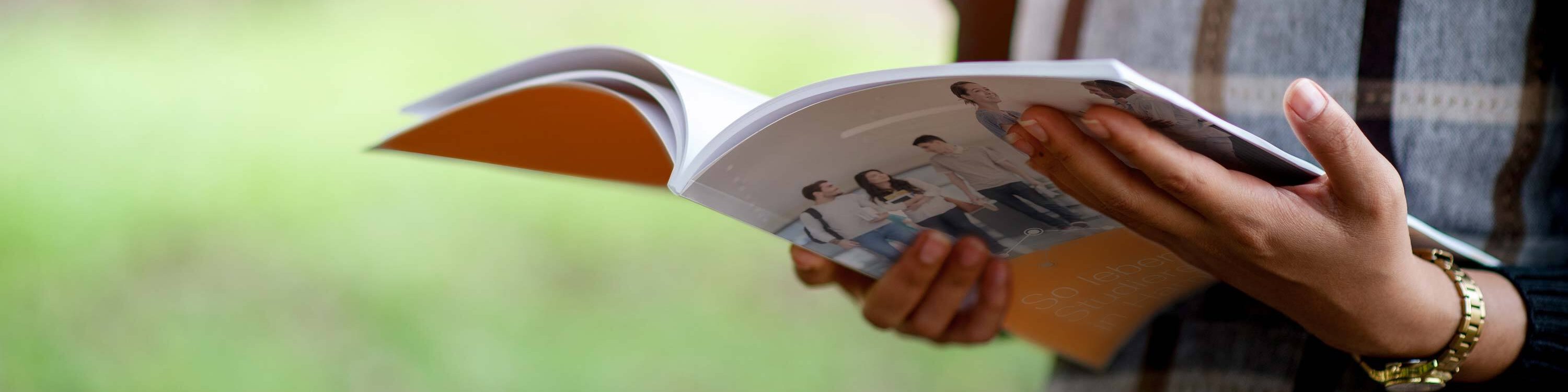 Frau im Park mit einem Magazin in den Händen