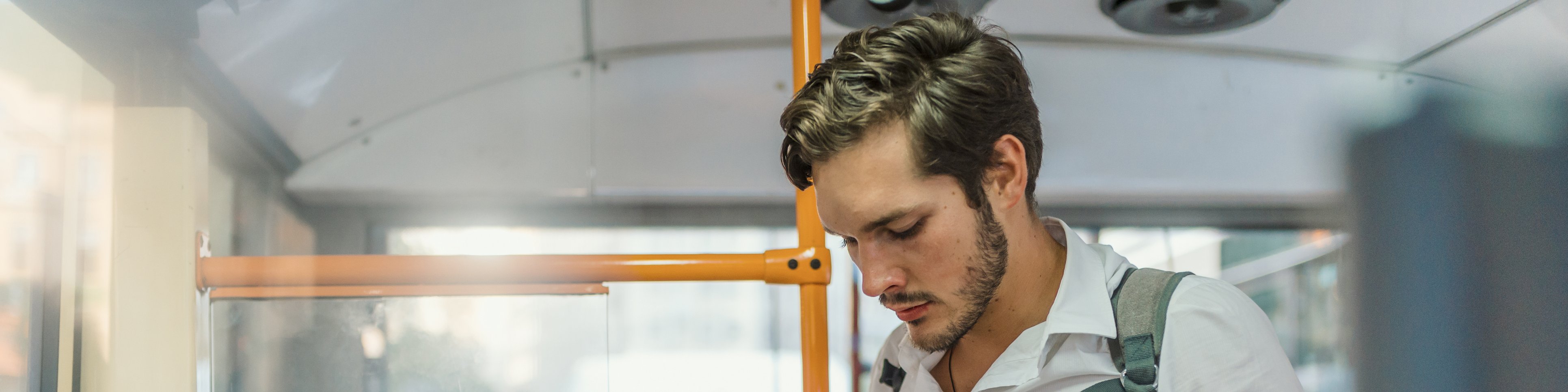 Junger Mann mit Handy steht im Bus 