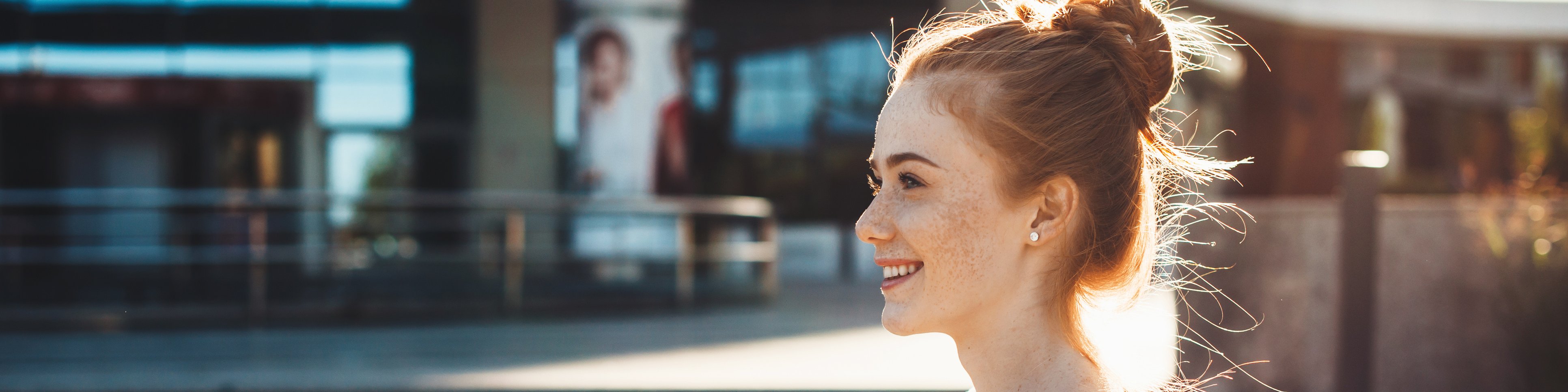 Young woman standing in front of a building holding books in her hands