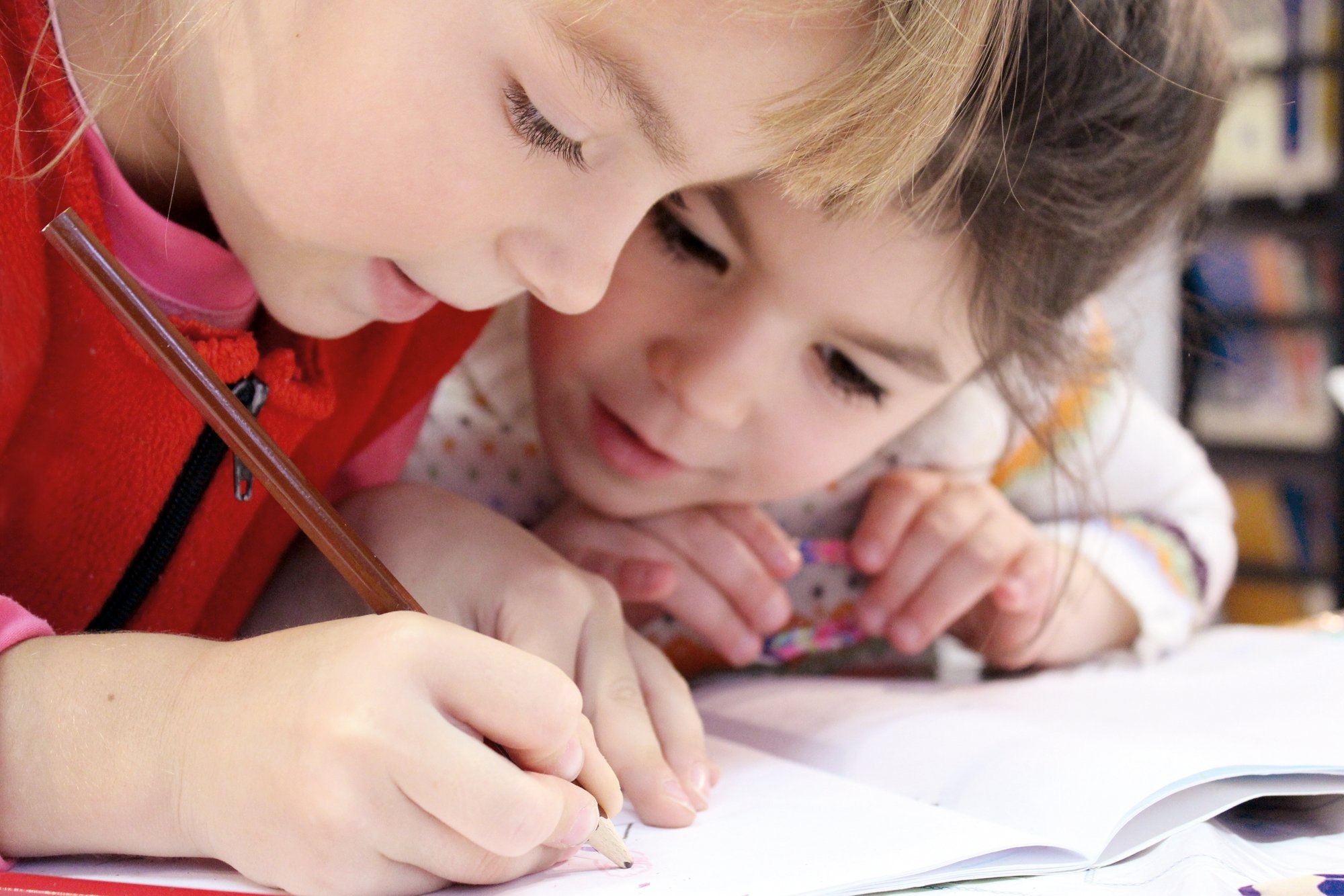 Two little girls are painting a picture together.
